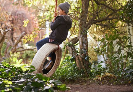 Boy, tyre swing and playing in garden with happiness, recreation and countryside vacation in summer. Child, smile and diy adventure playground in backyard of home with sunshine and trees in nature.