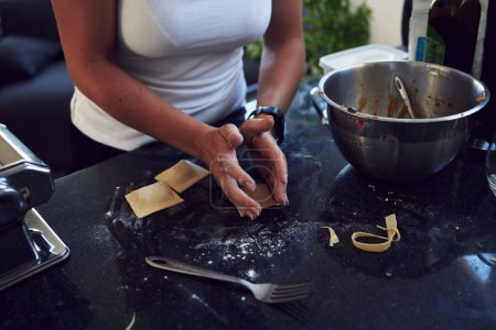 Foto de Persona, manos y cocinar pasta en casa con tazón y tenedor para una dieta saludable. Mujer, chef y comida con cuchillo para la nutrición, comida equilibrada y preparación artesanal de ravioles en mostrador. - Imagen libre de derechos