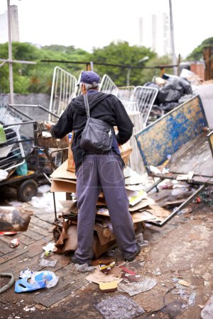 Man, worker and recycling of garbage for waste management in city with rear view, bag and scrapyard. Person, back and search by dumpster site for scrap, rubbish and trash in neighborhood for litter.