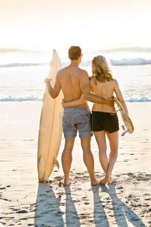 Téléchargez les photos : Planche de surf, câlin ou couple en mer pour l'aventure, anniversaire ou exercice sportif à Miami, Floride. Surfeurs en bonne santé, vue arrière ou personnes prêtes pour le surf en vacances à la plage ou à l'océan en été. - en image libre de droit