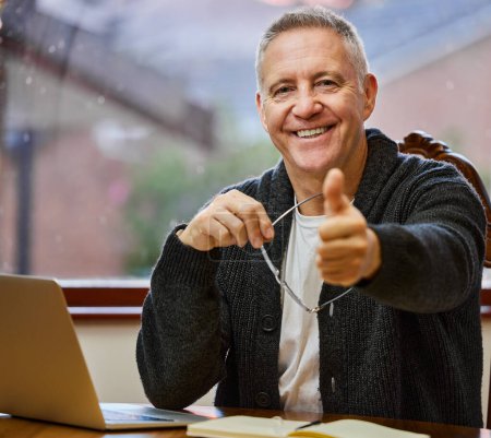 Portrait, senior man and laptop with thumbs up for remote work, agreement and schedule planning. Mature male therapist, home and emoji for yes with online counseling, telehealth and home on internet.