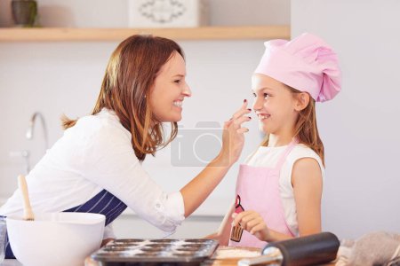 Téléchargez les photos : Mère, fille et touche de nez pour cuisiner dans la cuisine, le soutien et l'apprentissage de l'enfant à préparer des cupcakes. Bonne fille, maman et l'éducation de la pâtisserie à la maison, l'amour et la liaison tout en cuisinant des collations ou des desserts. - en image libre de droit