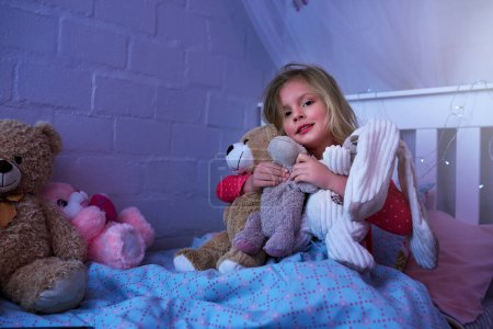 Photo for Girl, portrait and hug teddy bear on bed in house for sleeping, safety and calm or peaceful night. Female child, happy and stuffed animals in bedroom with toys for comfort, bedtime and dream in home. - Royalty Free Image