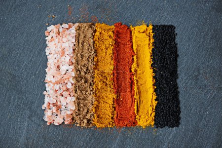 Photo for Row, spice and collection of powder for seasoning, turmeric and paprika for meal. Top view, condiments and options for spicy cooking in Indian culture, cumin and food preparation on table for aroma. - Royalty Free Image