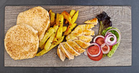Photo for Chicken, chips and salad prepared on chopping board for healthy nutrition, balanced diet and serving in restaurant. Fast food, fresh and delicious on cutting board for lunch, supper or dinner. - Royalty Free Image