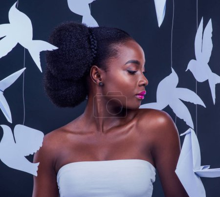 Afrikanische Frau, kreativ und schön mit Papiervögeln für Kunst, Mode und Vertrauen oder im Atelier. Schwarzes Modell, Fantasie und Make-up mit Origami für Dekor, Design und interkulturelle Vielfalt.