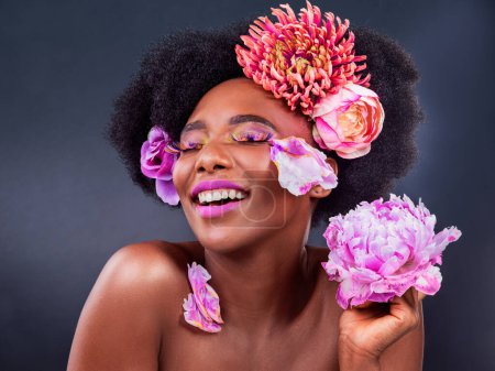 Photo for African, girl and beauty with flowers, smile and confidence for makeup, skincare and wellness in studio. Female person, pose and happy for fashion, style and luxury in grey background for cosmetics. - Royalty Free Image