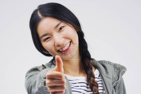 Photo for Studio, portrait and asian woman with thumbs up for agreement, deal and yes with mockup. Approval, smile and happy girl with good hand gesture, satisfaction expression or sign by white background. - Royalty Free Image