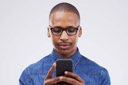 Photo for Black man, smartphone and typing by studio background for internet with web connection, social media and chat app. Male person, mobile and news website by grey backdrop with research and reading sms. - Royalty Free Image