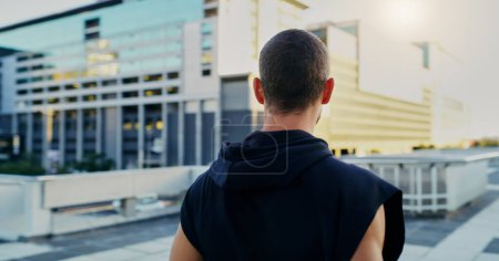 Photo for Back, fitness and man thinking in city for running, cardio workout or endurance training. Lens flare, sports and athlete for parkour preparation, exercise or thoughtful on rooftop in urban town. - Royalty Free Image