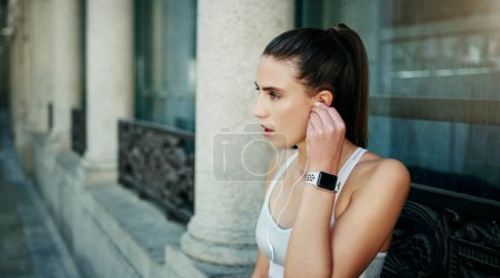 Téléchargez les photos : Earphones, woman or athlete in city ready for workout, training or outdoor exercise with radio music. Sports podcast, break or runner listening to audio for energy, wellness or fitness in England. - en image libre de droit