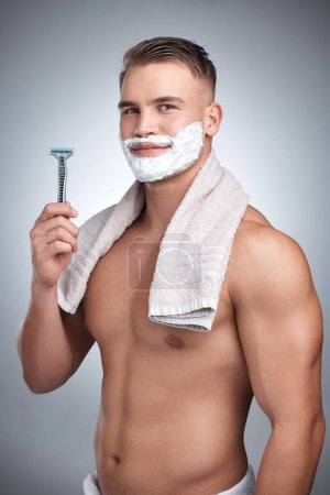Photo for Portrait, man and razor with hair removal in studio for grooming, shaving cream and towel by backdrop. Male person, body and happy with soap for skincare, beard and facial products by grey background. - Royalty Free Image