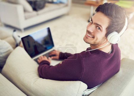 Homme, ordinateur portable et portrait avec écouteurs sur canapé à la maison avec streaming audio, service d'abonnement et jeux en ligne. Personne, musique et sourire sur l'application technologique pour le divertissement sonore, la radio et la playlist.