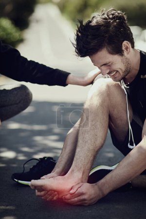 Photo for Friends, feet pain and injury outdoor for help in accident, exercise or man training on street with red glow. Foot, runner or massage for muscle problem, arthritis or fibromyalgia from sports workout. - Royalty Free Image