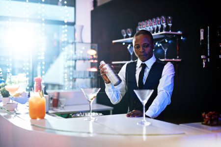 Photo for Black man, bartender and shake to prepare drink in restaurant, hospitality and counter server for alcohol. Male person, mix cocktail and martini at hotel bar, waiter confidence and barman selection. - Royalty Free Image
