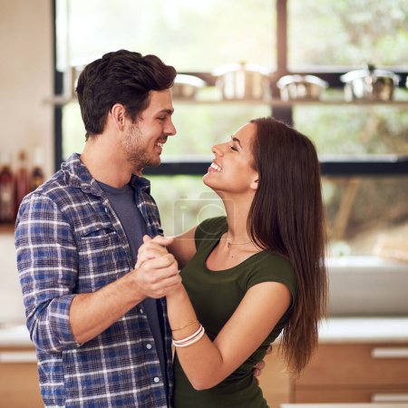 Photo for Happy, young couple and dancing together in kitchen for bonding, fun and romantic connection at home. Excited, man and woman with smile for holding hands, love and trust with rhythm in new apartment. - Royalty Free Image