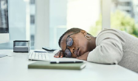 Foto de Mujer negra, escritorio y dormir con gafas en la fatiga, agotamiento o exceso de trabajo en la oficina. Africano cansado, mujer o empleado de negocios agotado descansando sobre la mesa para dormir la siesta por estrés o depresión. - Imagen libre de derechos