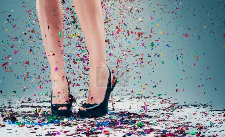 Photo for Woman, legs and heels with confetti for celebration of new years, party and decoration for event. Person, shoes and sparkling sequins on floor for festive, birthday and surprise on studio background. - Royalty Free Image