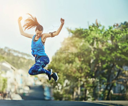 Photo for Woman, street and fitness with jump for celebration, speed and progress with training in summer. Girl, person or runner with cheers, winning and success for workout goals on road with achievement. - Royalty Free Image