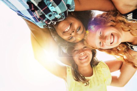Photo for Happy, low angle and portrait of children in summer for friendship, playing and fun together. Diversity, youth and girls huddle in circle for childhood, game and hug for school, recess and playground. - Royalty Free Image