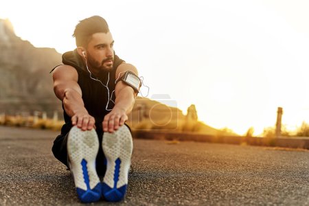 Photo for Man, fitness and headphones with stretching of legs on ground for exercise, workout or warm up music. Male person, idea and runner on mountain with preparation for muscle, training or sports podcast. - Royalty Free Image