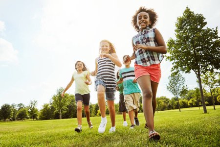 Photo for Happy friends, diversity and running with kids in nature for fun, playful day or summer at park. Group of excited children or youth enjoying sunny outdoor holiday or weekend on grass field together. - Royalty Free Image