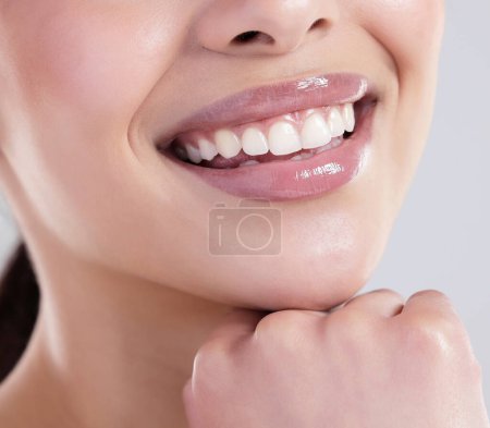 Foto de Mujer feliz, boca y dientes con confianza para el cuidado dental, higiene o tratamiento en un fondo gris estudio. Primer plano de la joven mujer con una gran sonrisa para blanquear los dientes, brillo de labios o brillo. - Imagen libre de derechos