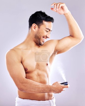 Foto de Hombre, aseo y sonrisa con desodorante en estudio fondo para higiene, limpieza y bienestar. Hombre, feliz y seguro de sí mismo con spray para el olor, la fragancia y la frescura corporal o la salud. - Imagen libre de derechos