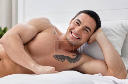Photo for Bedroom, portrait and man with smile, relax and health on bed, serious and thinking in morning. Home, muscle and fitness of body, abs and person in apartment, confidence and art on arm in house. - Royalty Free Image