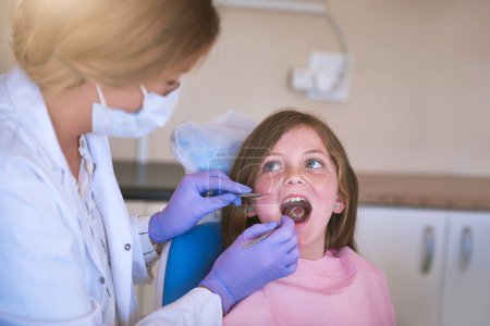 Photo for Child, woman dentist and mouth checking with oral hygiene and teeth care with patient and dental exam. Toothache, tooth cleaning and medical help with kid doctor and dentistry tool for healthcare. - Royalty Free Image