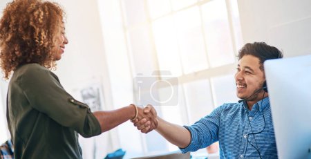 Foto de Business people, man and woman with handshake, call center and telemarketing with promotion. Modern office, coworkers and employees shaking hands, computer and agreement with support and thank you. - Imagen libre de derechos