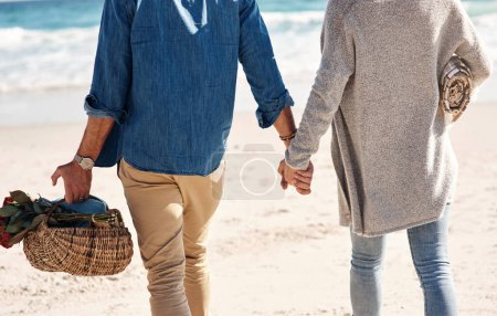 Téléchargez les photos : Couple, plage et se tenir la main ou marcher en vacances à l'océan ou à la mer avec amour. Été, Voyage et panier de pique-nique sur l'île avec des gens qui collent sur la date en plein air dans le mariage avec soin. - en image libre de droit