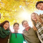 Tree, happy and people with smile in nature for outdoor friendship, vacation and bonding together. Low angle, hug and group of teens in park for support, adventure and break on holiday in Australia.