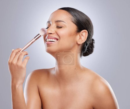 hand with brush, face and cosmetics of woman by studio background for wellness, beauty and makeup. Nose, female model and product for application, foundation and facial treatment with confidence.