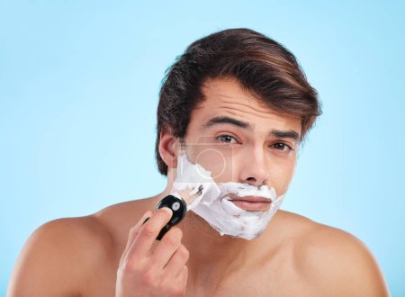 Photo for Portrait, man and shaving cream brush in studio for hair removal, hygiene and grooming isolated on blue background. Face, beard and model apply foam for skincare, beauty and cleaning for wellness. - Royalty Free Image