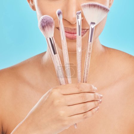 Photo for Creative, makeup and girl with brushes in hand for application of cosmetics in blue background. Studio, beauty and artist with tools to apply foundation, powder or product in skincare with smile. - Royalty Free Image