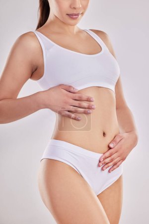 Photo for Fitness, underwear and hand of woman on stomach for wellness, digestion and lose weight body campaign. Diet, abdomen and healthy gut of model in studio on white background touching bely for slimming. - Royalty Free Image