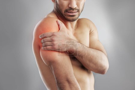 Photo for Man, shirtless and shoulder injury in studio with muscle pain for physiotherapy, massage and healthcare. Fitness model, body and red glow for xray, wellness and physical therapy on gray background. - Royalty Free Image