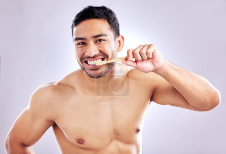 Foto de Higiene, retrato y hombre con cepillo de bambú para dientes, sostenibilidad y biodegradable del producto. Estudio, fondo blanco y limpieza de dientes para persona, aseo y salud bucal con madera. - Imagen libre de derechos