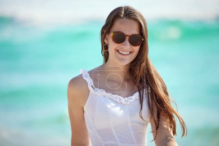 Photo for Beach, woman and sunglasses for walk while happy on vacation, holiday and journey in California. Female traveler, ocean and nature for peace, relaxing and enjoying summer trip with confident girl. - Royalty Free Image