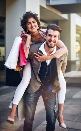 Photo for Shopping mall, piggy back and portrait of couple in city for clothing sale, discount deal and store promotion. Fashion, retail and happy man and woman for bonding, travel and tourism in urban town. - Royalty Free Image