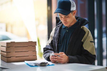 Photo for Fast food, delivery man and pizza and phone in office for distribution, online order and courier service in city. Sign in, ecommerce and person with boxes for lunch, dinner and supper on smartphone. - Royalty Free Image