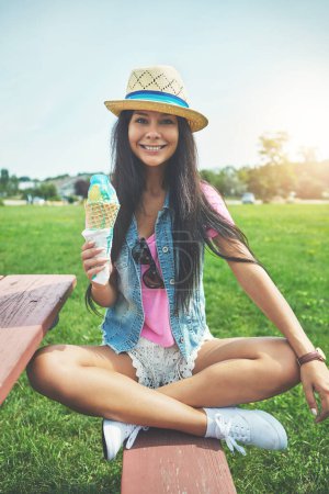 Photo for Girl, portrait and ice cream cone at park sitting on bench with vanilla or bubblegum flavor for summer. Woman, happy and gelato dessert at garden with sunshine or smile for relax, vacation and nature. - Royalty Free Image