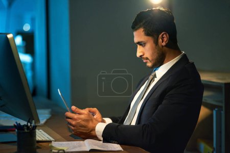 Photo for Businessman, office and phone by table at night for career, advocate or lawyer with research. Male person, computer and mobile by desk for work at law firm, plan for justice or court with technology. - Royalty Free Image