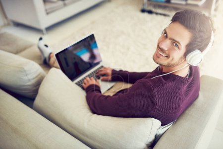 Photo for Man, laptop and portrait with music on sofa in home with top view for audio streaming, subscription service and online gaming. Person, headphones and happy for sound entertainment, radio and playlist. - Royalty Free Image