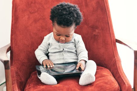 Téléchargez les photos : Bébé, garçon et en ligne avec tablette sur canapé avec apprentissage numérique pour la petite enfance ou le développement cognitif et la croissance. Tout-petit, la technologie et se détendre à la maison avec une application sensorielle ou un jeu pour la motricité. - en image libre de droit