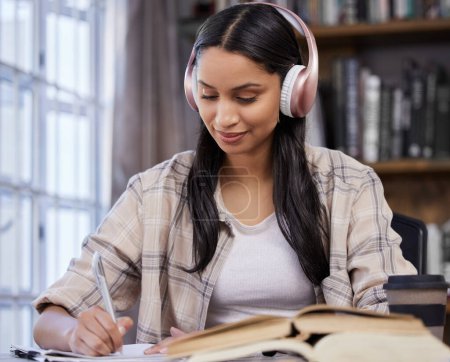 Photo for Headphones, study and girl with notebook in library for music, learning or studying for exam. University, student and writing with technology on table for knowledge, development or streaming of audio. - Royalty Free Image