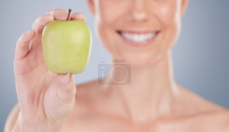 Photo for Beauty, diet and apple in hand closeup for nutrition benefits in studio background with wellness. Healthy, eating and person with food for vitamin c, antioxidants and fruit for skincare and happiness. - Royalty Free Image
