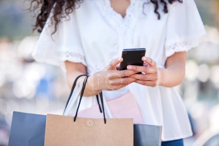 Foto de Woman, shopping and city or smartphone with hands, retail deal and customer with bags for online sale notification. Internet, tech and ecommerce app, texting and black friday offer or buying special. - Imagen libre de derechos