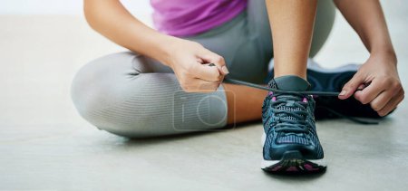 Téléchargez les photos : Tie, shoes and hands of woman with exercise fashion or start of fitness routine on floor with feet. Workout, gear or runner prepare sneakers for training in gym with laces and closeup on footwear. - en image libre de droit